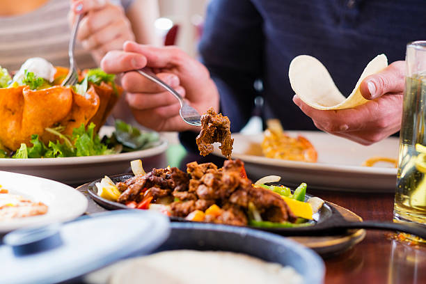 Alt Text: "Friends gathering around the table enjoying homemade fajitas, highlighting the social aspect of Tex-Mex cuisine."
